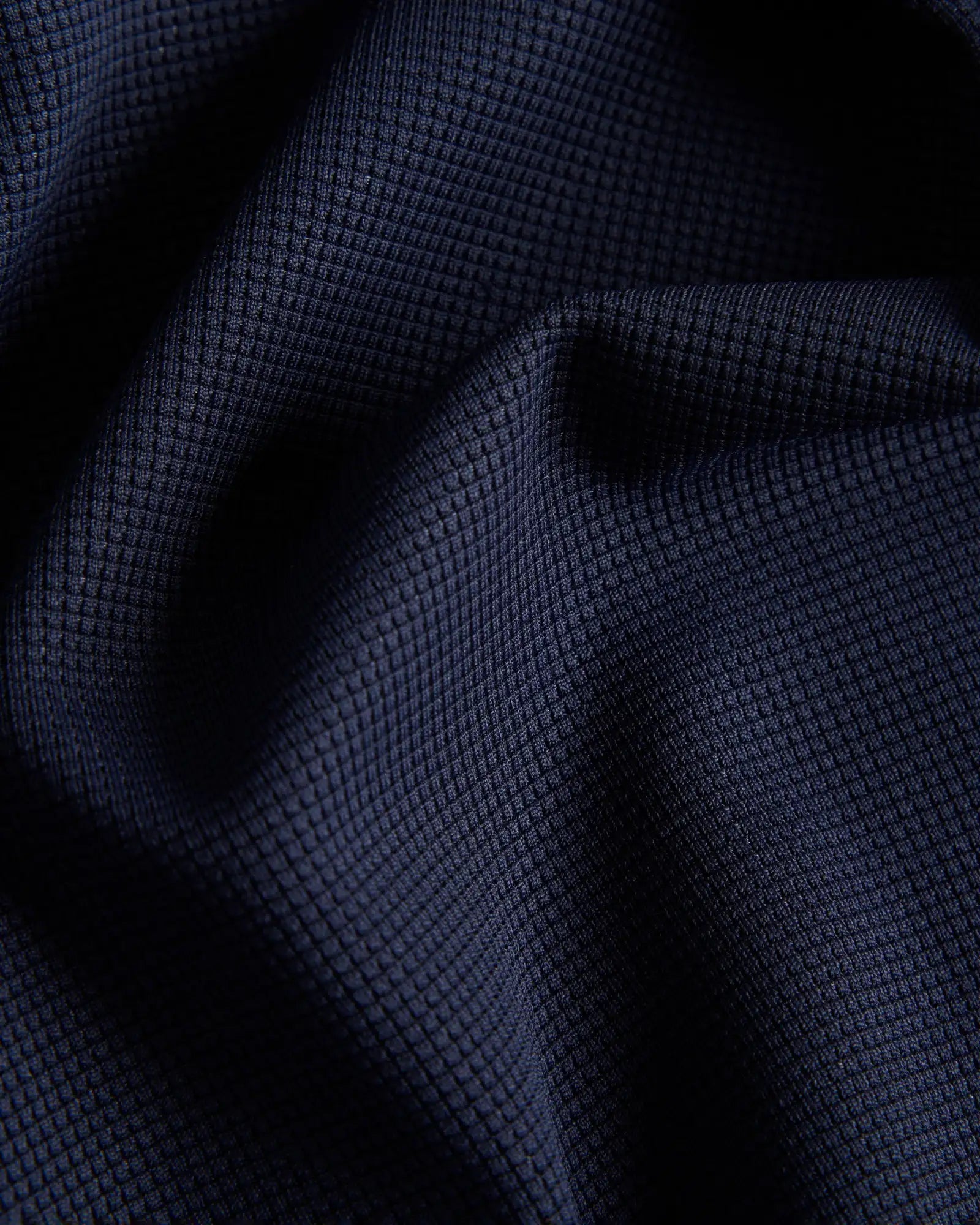 Dunkel marineblaues Waffelstrickgewebe mit einem texturierten, gitterartigen Muster.