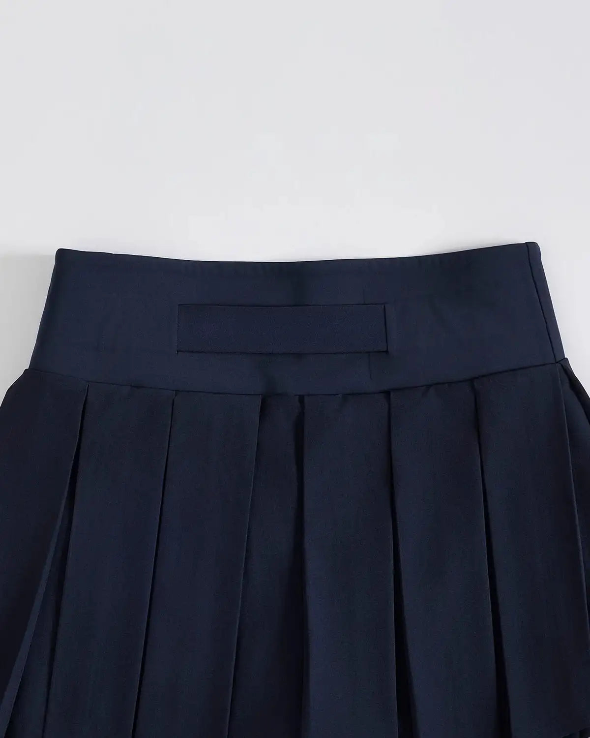 Marineblaue Plisseerock mit hochgeschnittenem Design und rechteckigem Patch am Bund