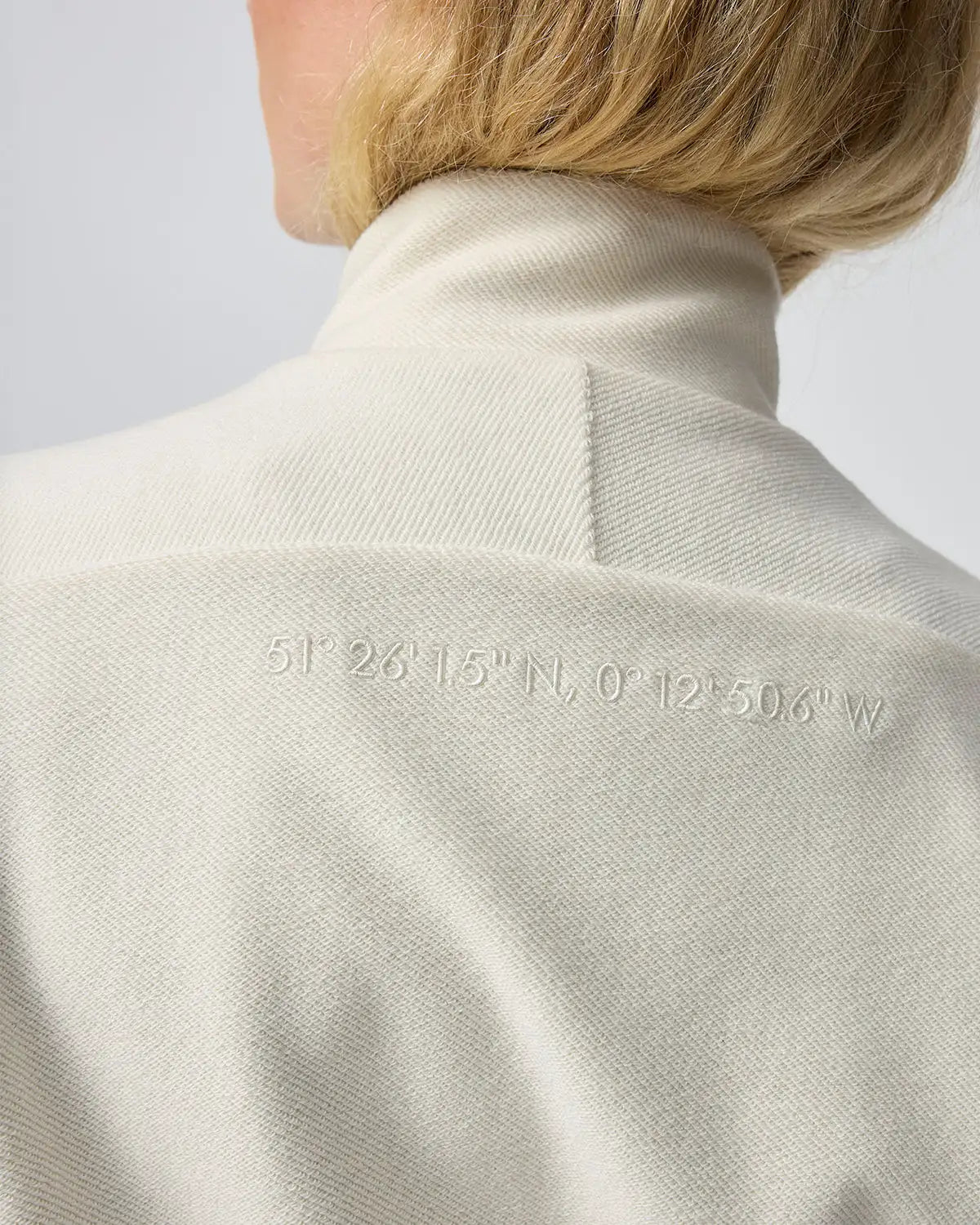 Cremeweißer Hochgeschlossener Blazer mit dezent gestickten Koordinaten auf dem Rücken.