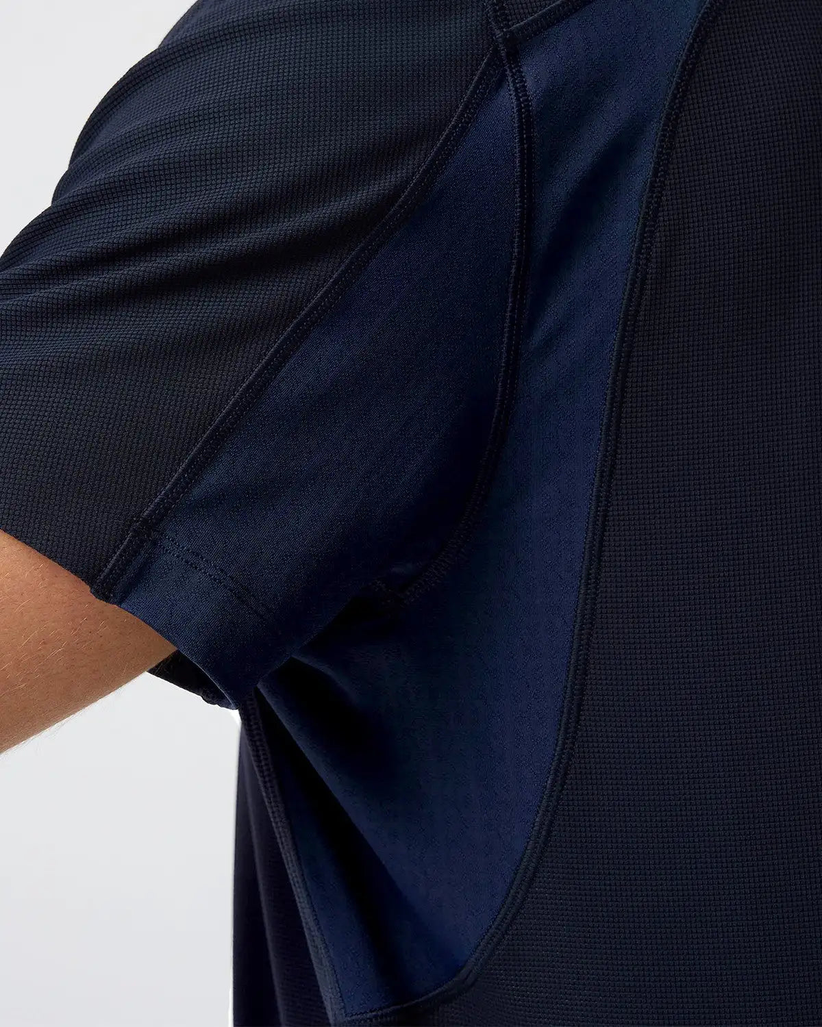 Dunkelblaues Sportshirt mit texturierter, atmungsaktiver Stofffaser und nahtloser Verarbeitung entlang der Schulternaht.