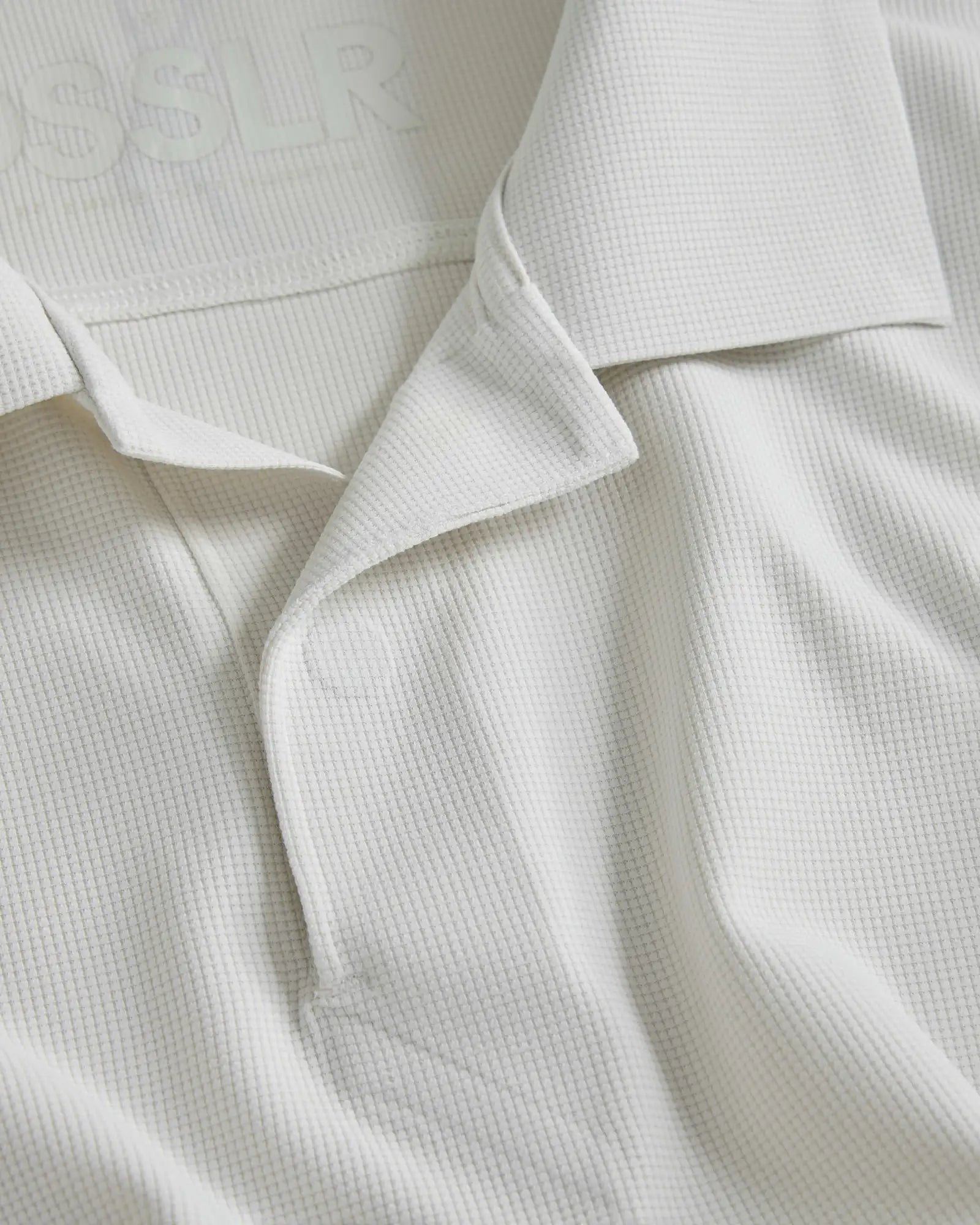 Weißes Poloshirt mit Textur und dezentem Gewebemuster sowie klassischem Kragen.