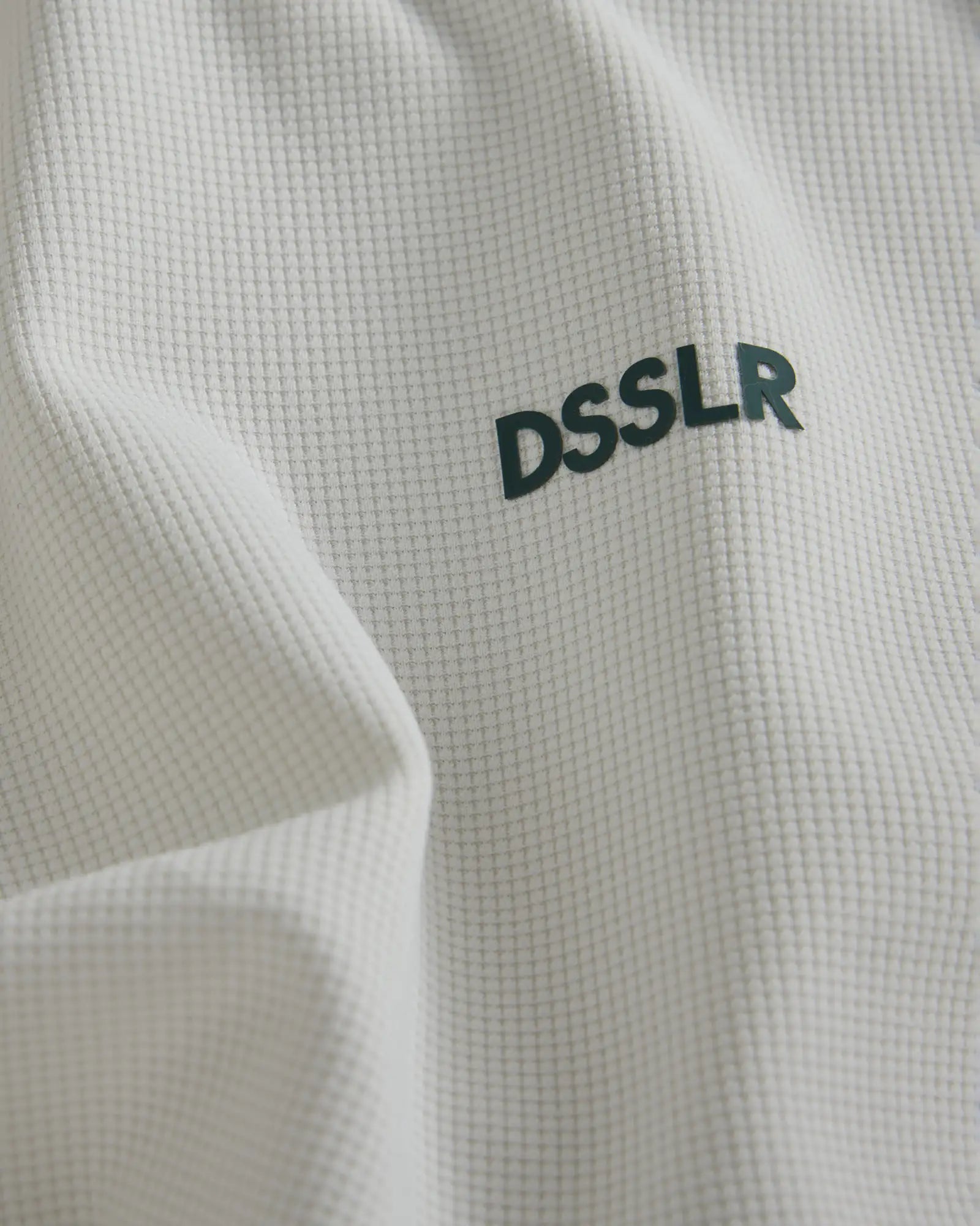 Weißes Waffelstrick-Gewebe mit dunkelgrüner ’dsslr’ Beschriftung.